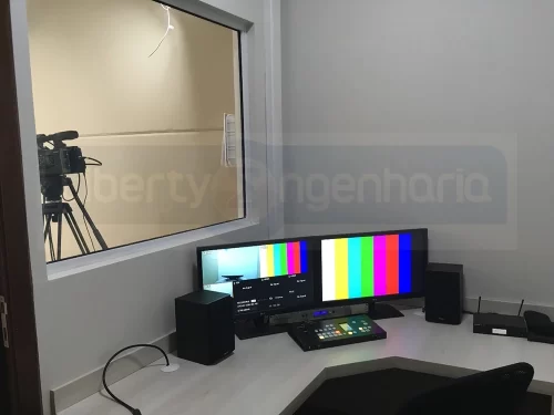 Mesa com equipamentos de audiovisual com janela para studio