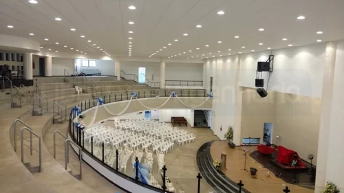 Salão principal da Igreja Batista com visão para o térreo com cadeiras, púlpito, auditório do primeiro andar e teto iluminado com revestimento acústico