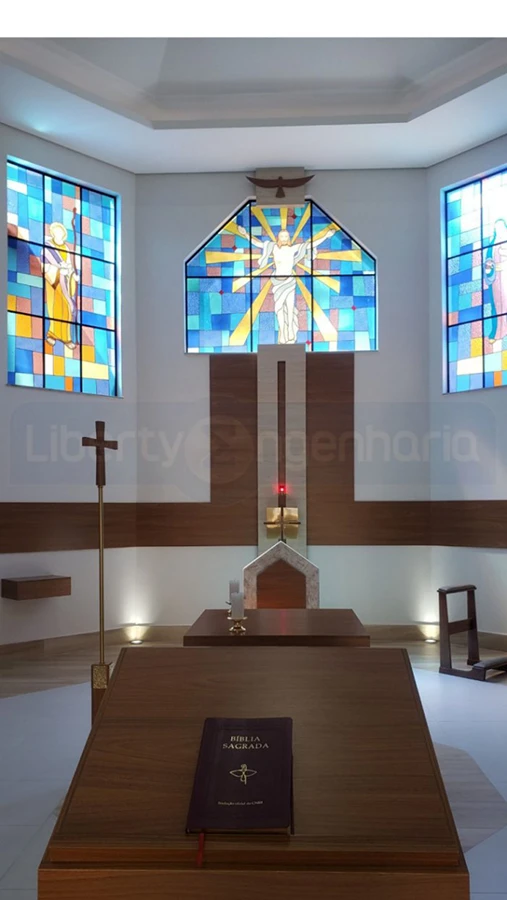 Parede do altar cor branca com linhas de madeira, vitrais azul e um pulpito