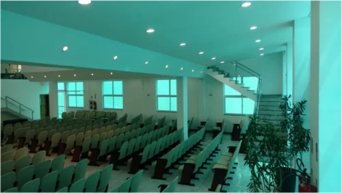 Cadeiras dispostas no salão principal de uma igreja com escadas de acesso para o primeiro andar
