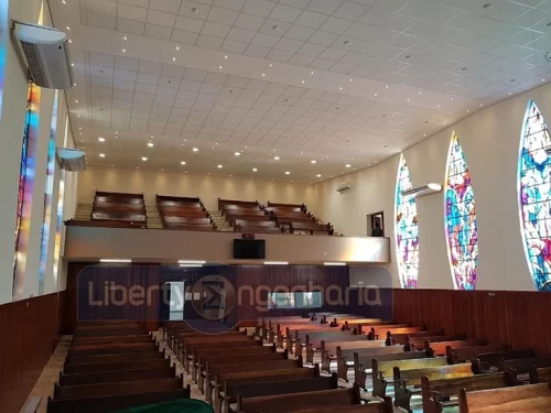 Salão principal de Igreja com bancos de madeira e vitrais coloridos nas paredes