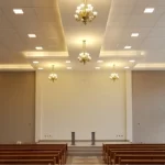 Salão de Igreja com lindos lustres e bancos de madeira dispostos