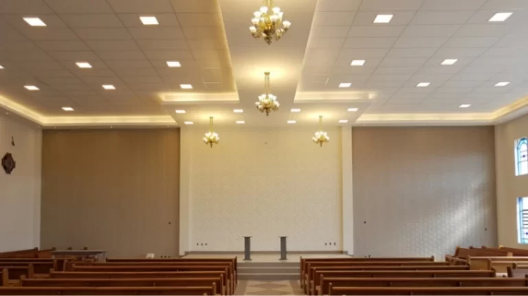 Salão de Igreja com lindos lustres e bancos de madeira dispostos