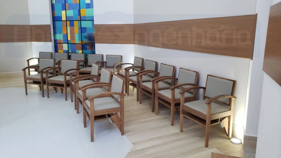 Cadeiras e vitral colorido em capela revestida com painel acústico