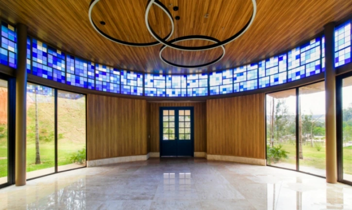 Vista do salão da capela com formato arredontado e vitrais azul