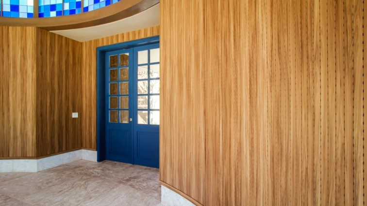 Entranda da capela com paredes de madeira e uma porta azul